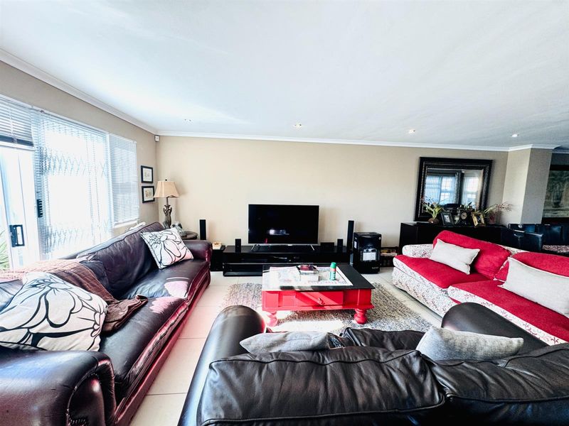 Spacious living room featuring tiled flooring, recessed ceiling lighting, and large sliding glass doors providing access to the outdoor area.