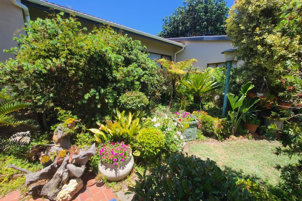 A lush, well-established rear garden featuring mature plantings, a brick-paved area, and a garden lamp post against the rear building facade.