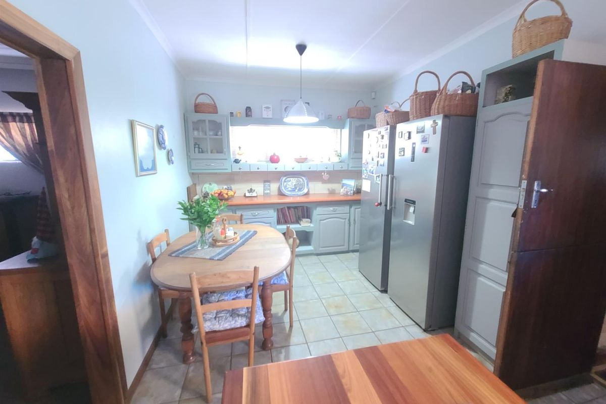 A functional kitchen featuring fitted cabinetry, tiled flooring, and built-in shelving, offering a practical layout for daily meal preparation.