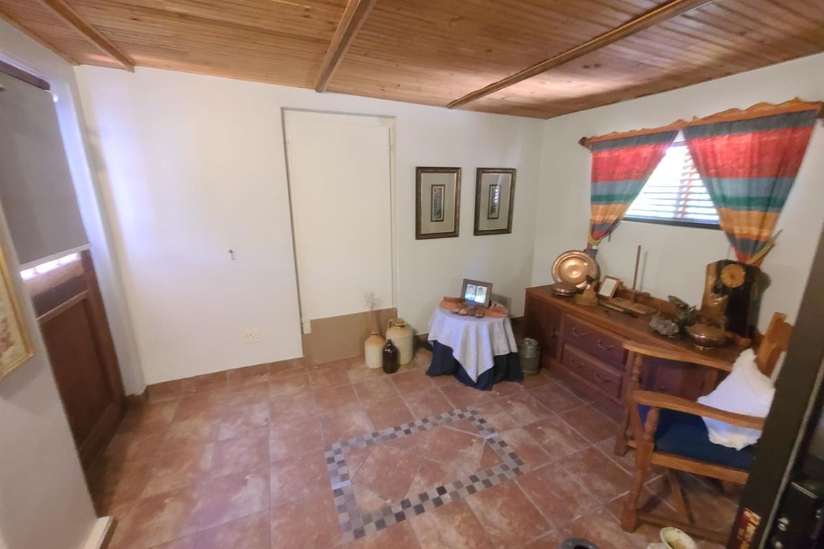 A living area featuring a warm timber-clad ceiling and tiled flooring with a decorative central inlay, offering a rustic aesthetic.