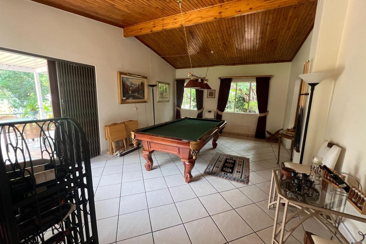 Spacious living area featuring a vaulted timber-clad ceiling, tiled flooring, and direct access to an outdoor patio through sliding security doors.
