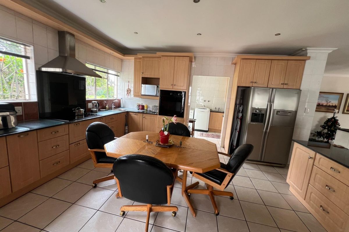 Spacious kitchen featuring light wood cabinetry, integrated oven, stainless steel extractor fan, and tiled flooring, with an adjacent scullery area.