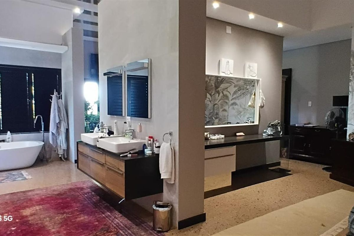 Spacious modern bathroom featuring a freestanding bathtub, double vanity with wall-mounted mirrors, and elegant terrazzo flooring with recessed lighting.