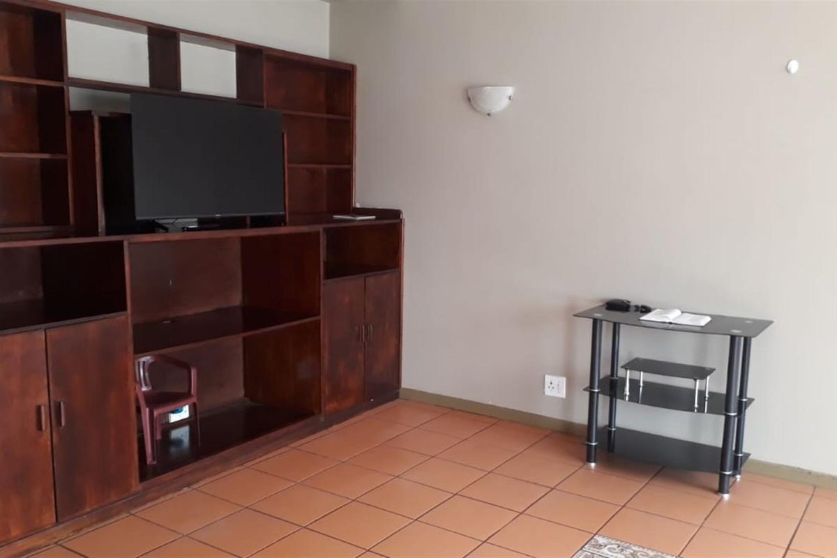 A living room area featuring built-in wooden cabinetry and tiled flooring, providing a functional space for storage and entertainment.