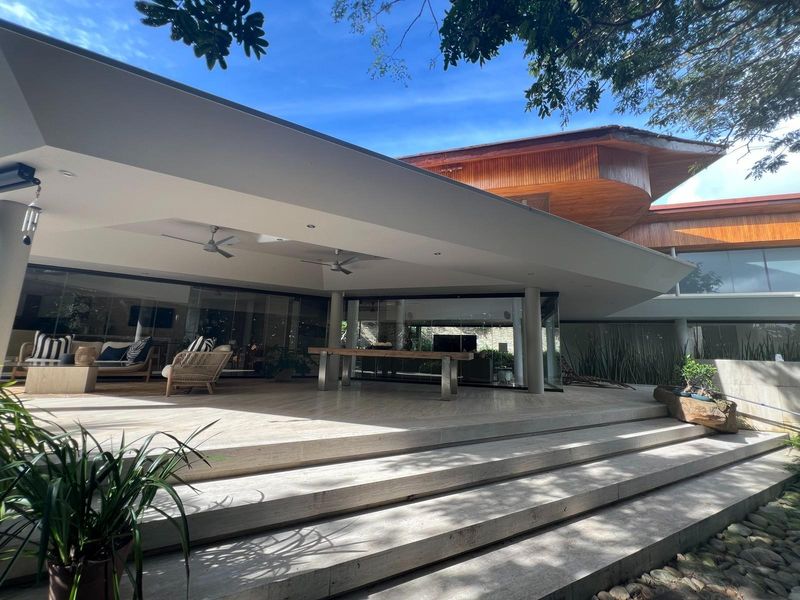 Spacious covered patio featuring stone flooring, recessed lighting, ceiling fans, and large glass sliding doors connecting to the interior living space.