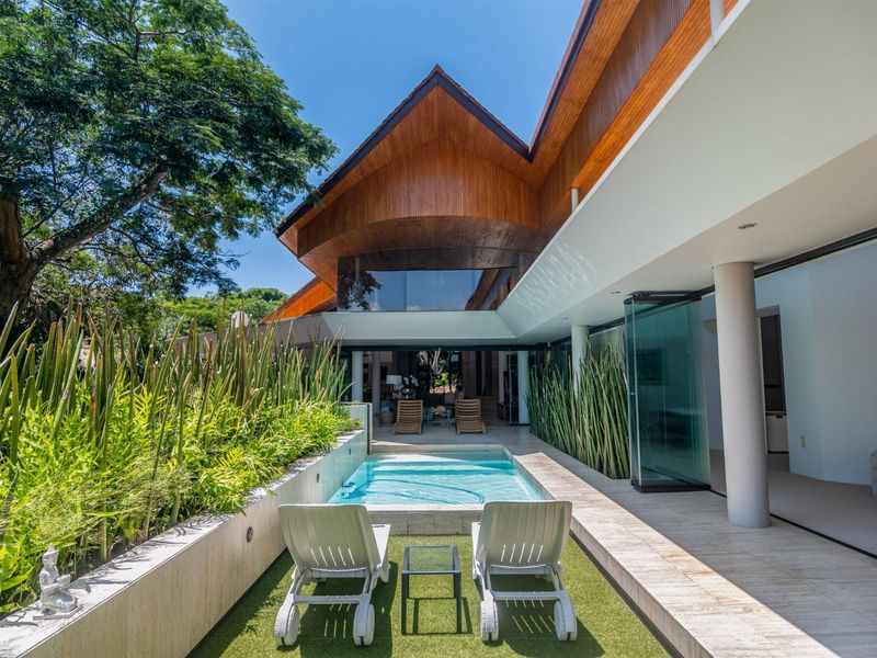 A modern outdoor pool area featuring a sleek swimming pool, stone decking, and seamless indoor-outdoor flow with large glass sliding doors.