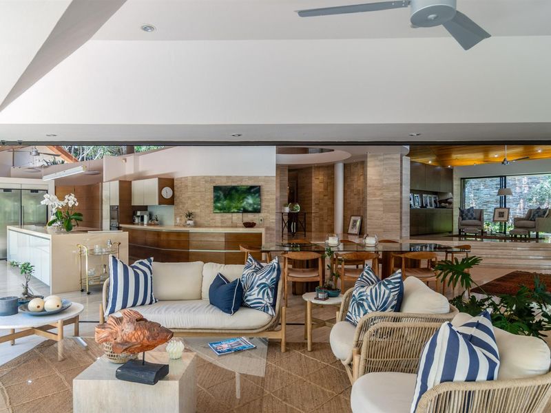 Spacious open-plan living, dining, and kitchen area featuring high-end finishes, stone wall accents, and seamless indoor-outdoor flow.