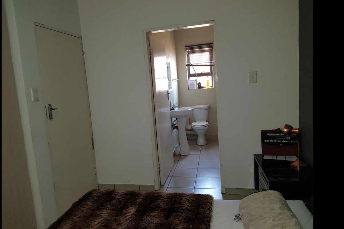 A bedroom featuring an en-suite bathroom with a pedestal basin and toilet, accessible via a standard doorway.
