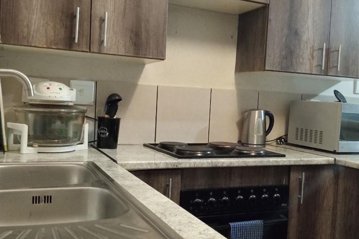 A functional kitchen featuring wood-look cabinetry, a stainless steel double sink, and a built-in electric oven with a four-plate hob.