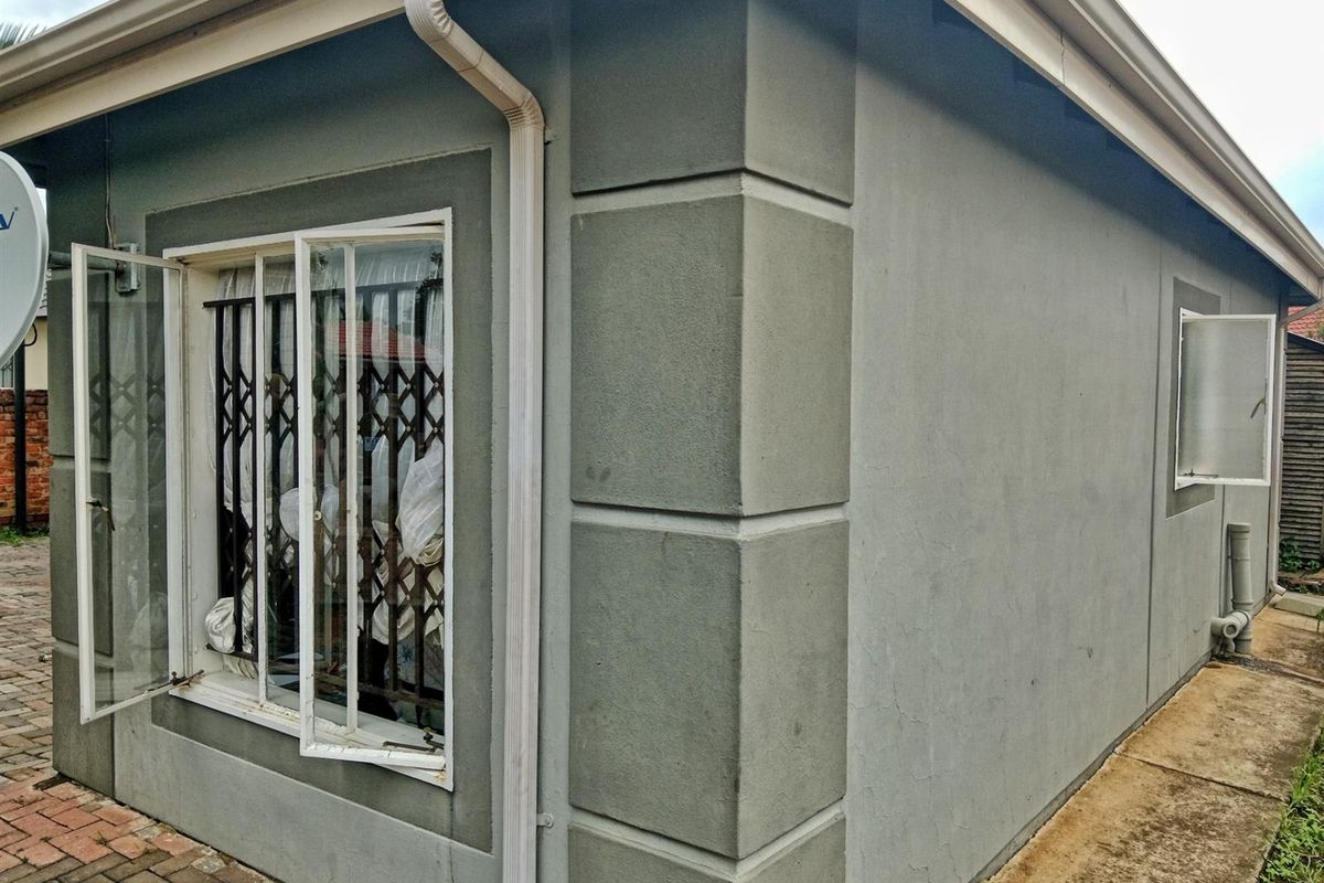 A view of the rear exterior wall featuring a security gate, casement windows, and functional guttering system.
