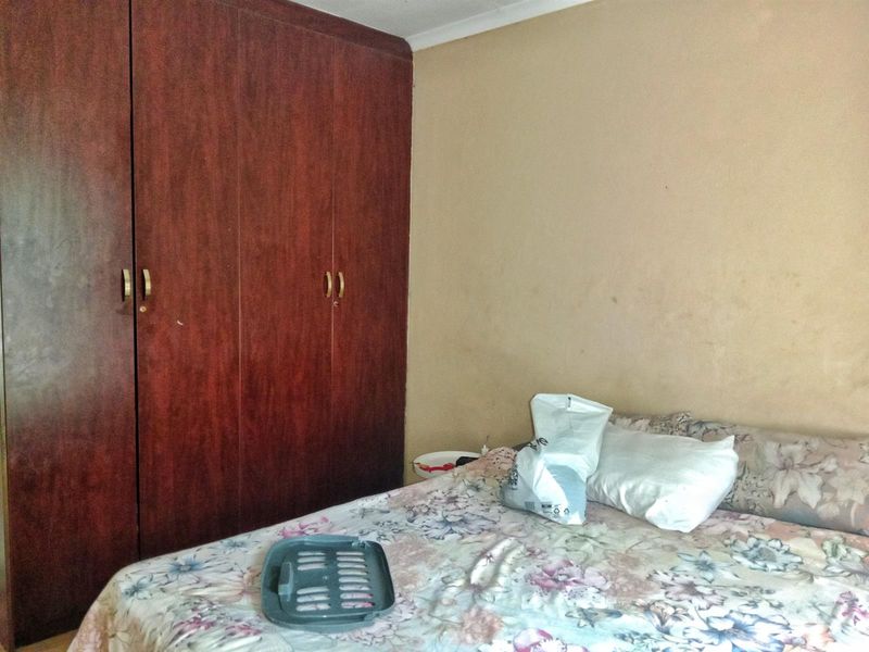 A bedroom featuring a large built-in wooden wardrobe and neutral wall finishes.