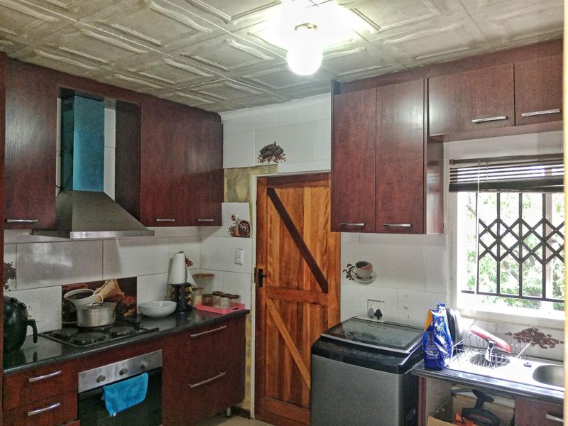 A functional kitchen featuring dark wood cabinetry, a gas hob with extractor, and a tiled ceiling, offering a practical layout for daily cooking.