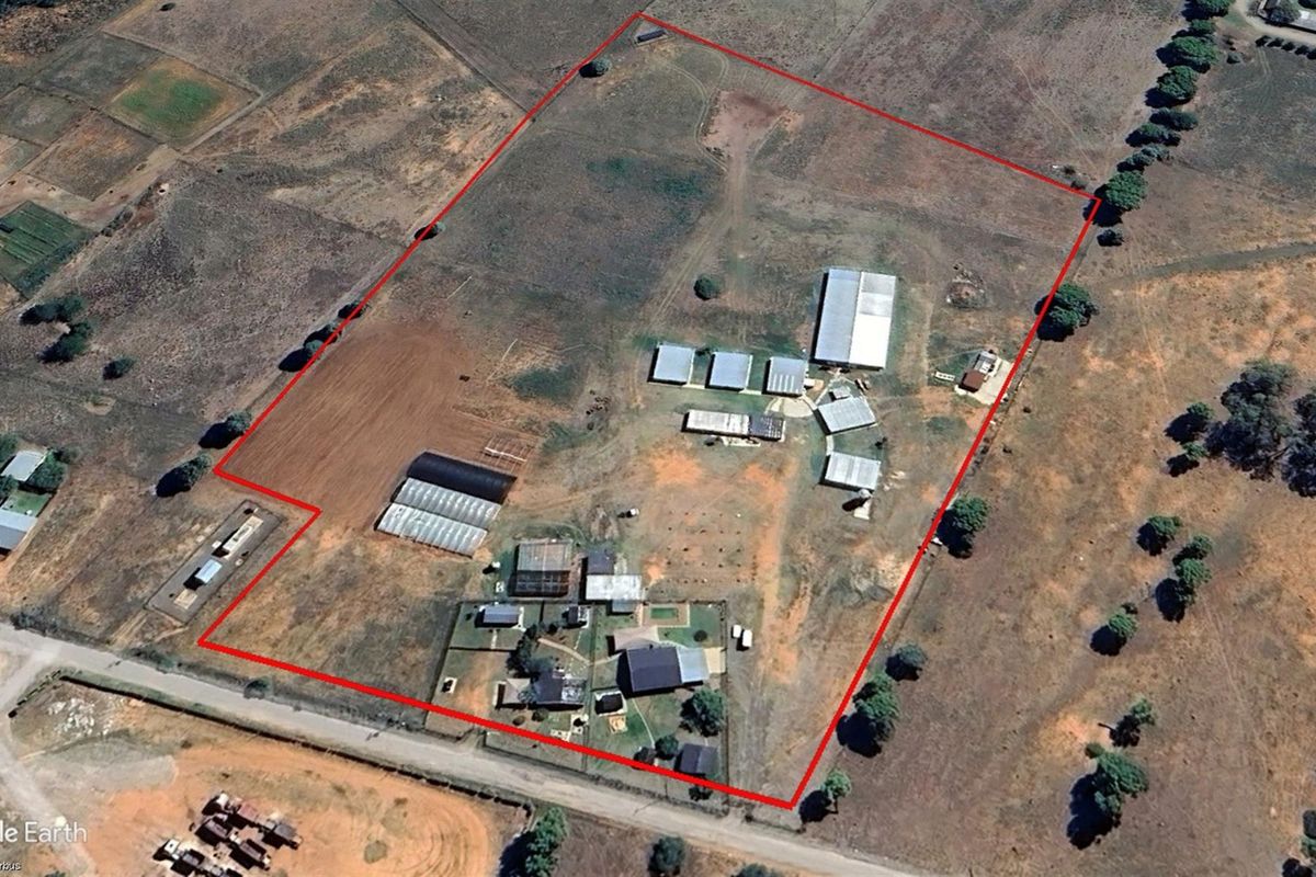 Aerial view of a large small holding property featuring multiple outbuildings, agricultural structures, and expansive open land within a clearly defined boundary.
