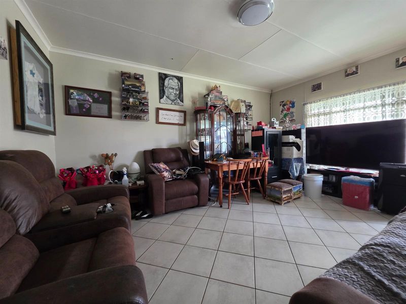 A spacious living room featuring neutral tiled flooring and a ceiling-mounted light fixture, providing a functional and comfortable living area.