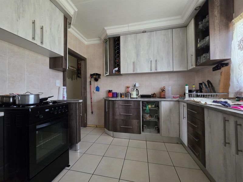 A functional kitchen featuring two-tone cabinetry, tiled flooring, tiled splashbacks, and a built-in gas stove with oven.