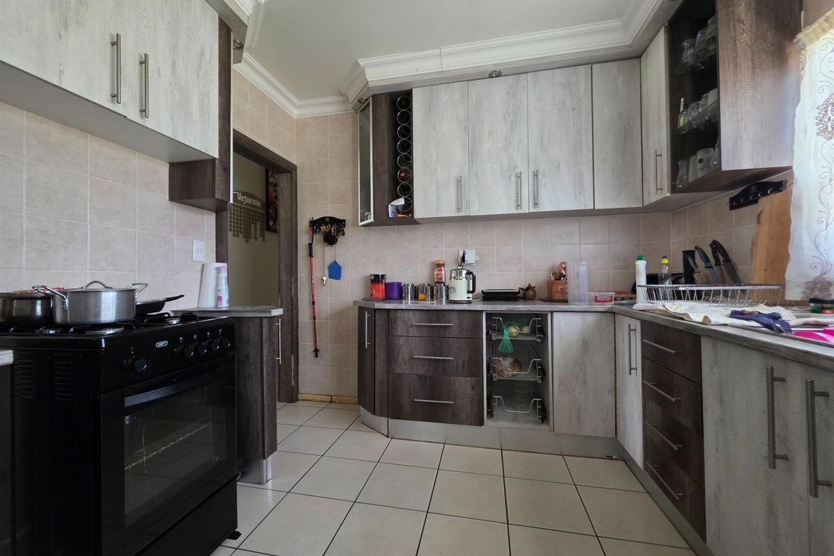A functional kitchen featuring two-tone cabinetry, tiled flooring, tiled splashbacks, and a built-in gas stove with oven.
