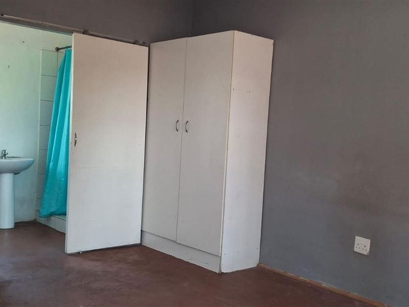 A bedroom featuring dark grey walls, a built-in wardrobe, and an en-suite bathroom with a pedestal sink and shower.
