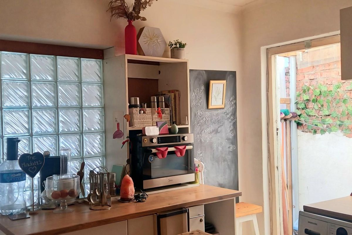 A functional kitchen area featuring a built-in oven, wooden countertops, and a unique glass block window, providing natural light and practical workspace.