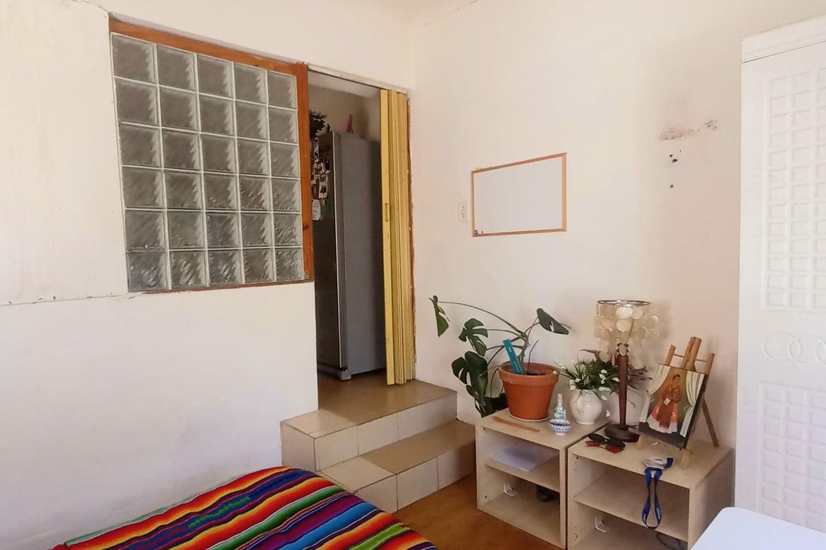 A bedroom featuring a glass block window, tiled steps leading to an adjacent area, and a built-in wardrobe with visible wall surface wear.