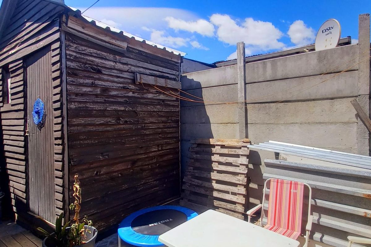 Rear outdoor area featuring a weathered timber shed and precast concrete boundary walling.