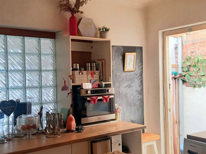 A functional kitchen area featuring a built-in oven, wooden countertops, and a unique glass block window, providing natural light and practical workspace.