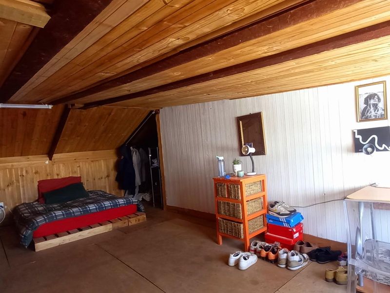 Attic-style bedroom featuring timber-clad walls and a sloped ceiling, providing a cozy and rustic living space.