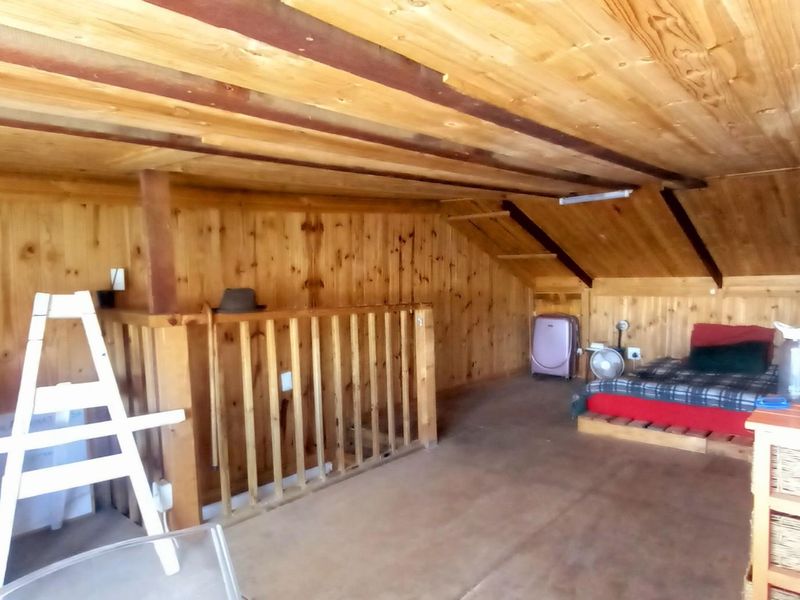 An attic-style bedroom featuring extensive timber wall and ceiling cladding with exposed beams and a wooden balustrade.