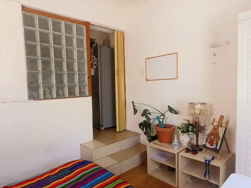 A bedroom featuring a glass block window, tiled steps leading to an adjacent area, and a built-in wardrobe with visible wall surface wear.