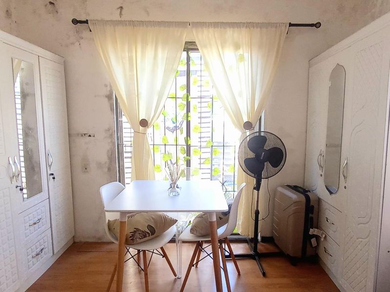 Bedroom featuring built-in wardrobes, laminate flooring, and security bars on the window. The room requires maintenance due to visible wall and ceiling staining.