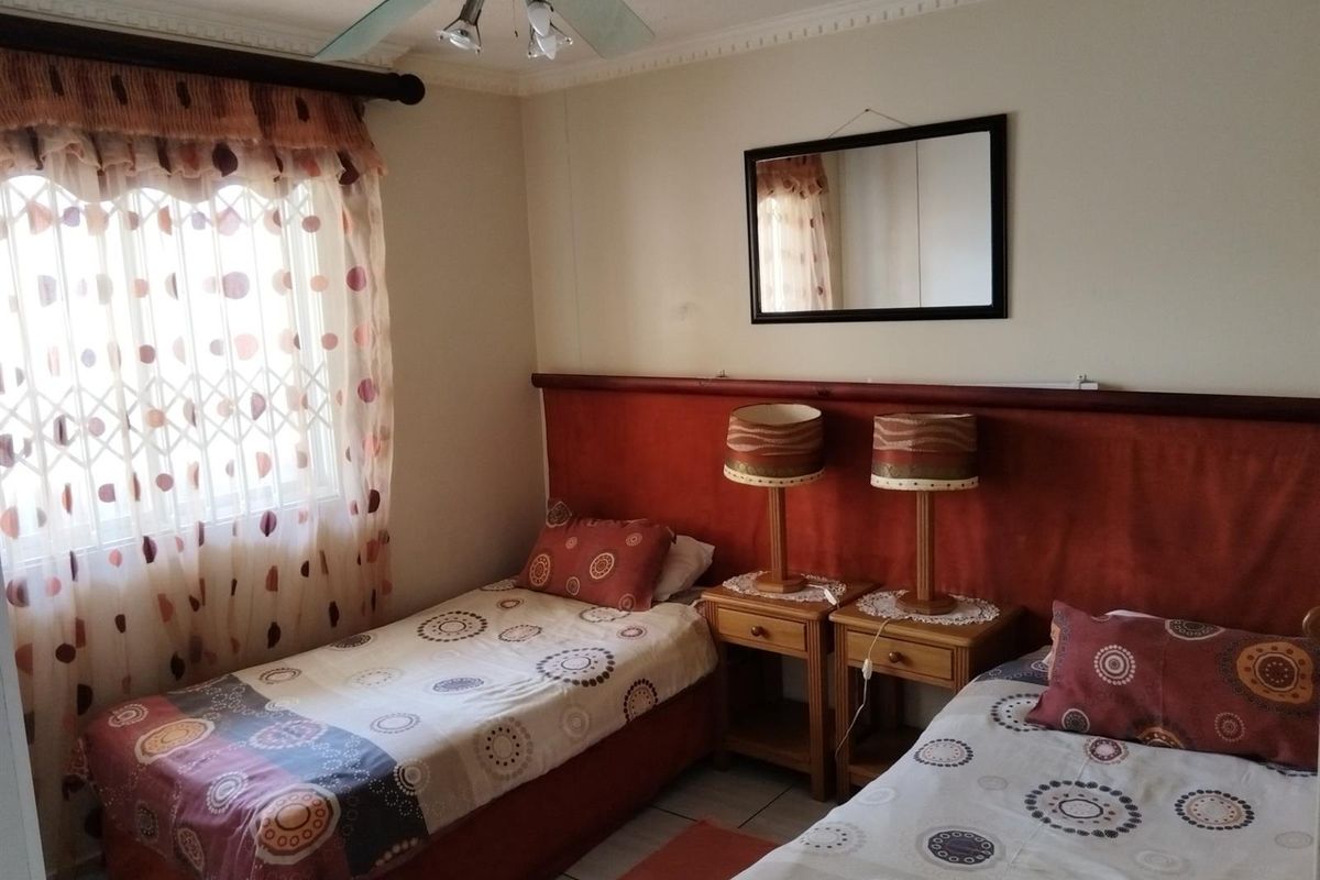 A bedroom featuring a built-in headboard, ceiling fan, and tiled flooring, providing a functional sleeping space.