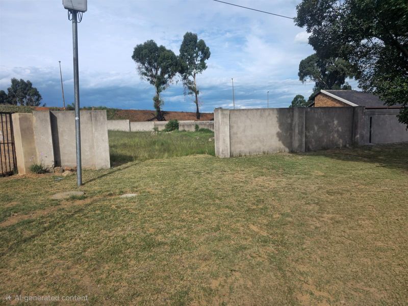 A vacant residential plot featuring established perimeter walling and open grassed area, offering a blank canvas for future development.