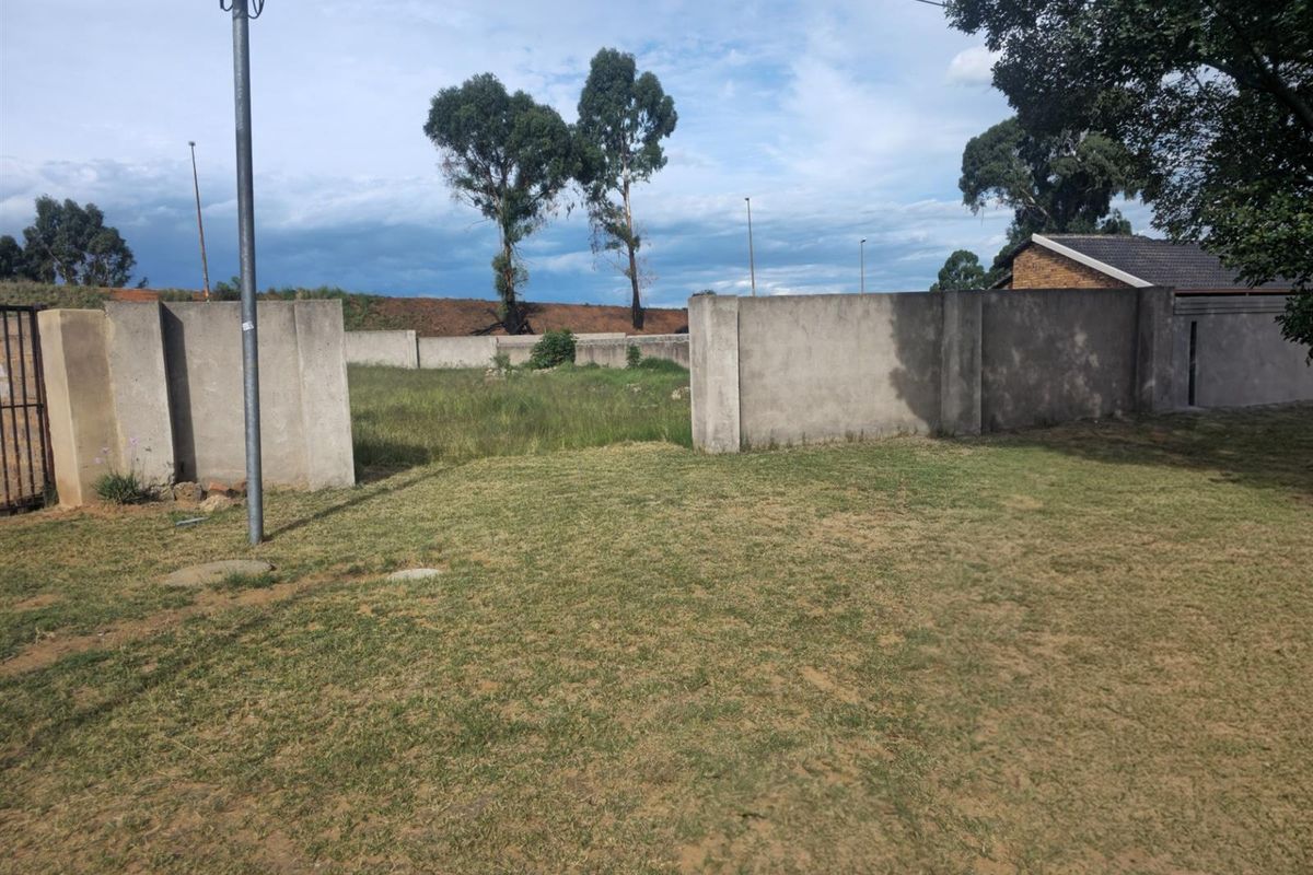 A vacant residential plot featuring established perimeter walling and open grassed area, offering a blank canvas for future development.