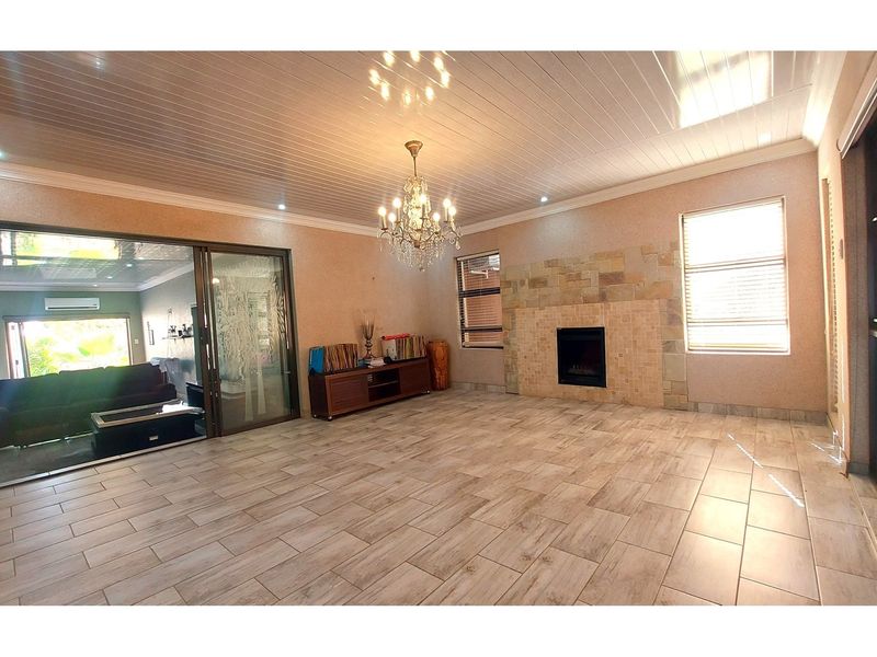 Spacious living room featuring tiled flooring, a stone-clad fireplace, and large sliding glass doors that provide ample natural light and access to the patio.