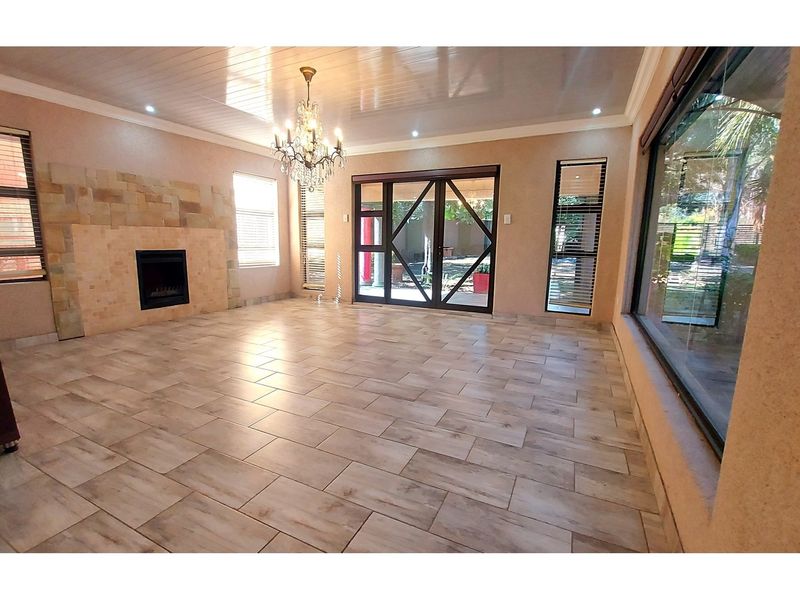 Spacious living room featuring tiled flooring, a stone-clad fireplace, recessed lighting, and large sliding glass doors leading to the garden.