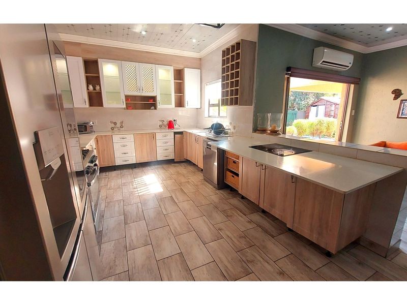 Modern kitchen featuring light wood cabinetry, stone countertops, integrated hob, and tiled flooring, with direct access to the outdoor area.