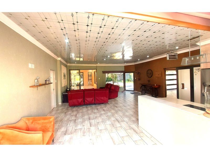 Spacious open-plan living area featuring tiled flooring, a unique patterned ceiling, and a kitchen island, with direct access to the outdoor patio.