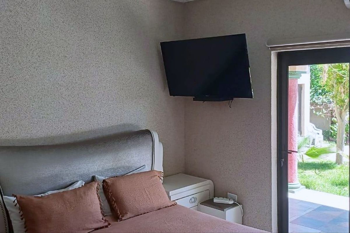 A bedroom featuring textured walls, an air conditioning unit, and a sliding glass door providing direct access to the garden.