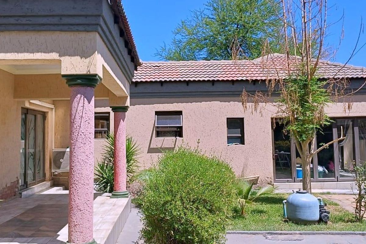 Rear view of the property featuring a covered patio, sliding glass doors, and a garden area with a pool pump.