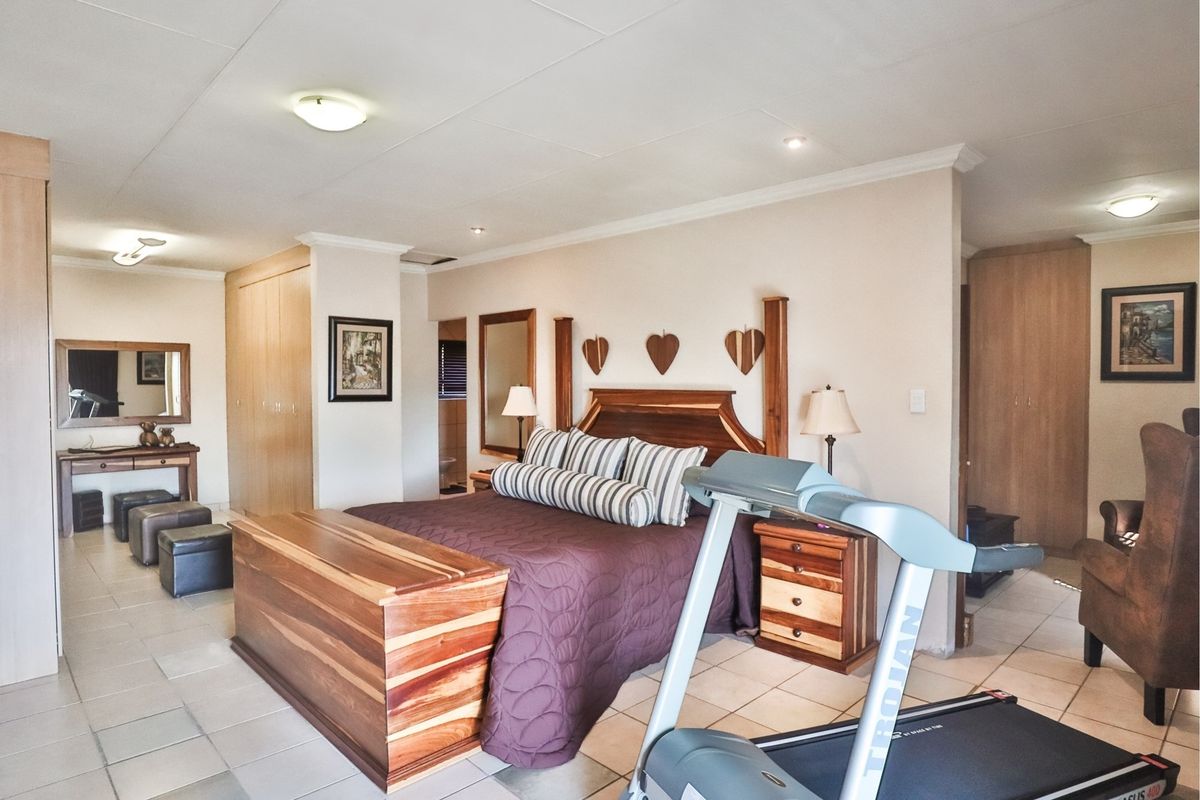 Spacious bedroom featuring built-in cupboards, tiled flooring, and neutral wall finishes, offering a functional layout with integrated storage solutions.