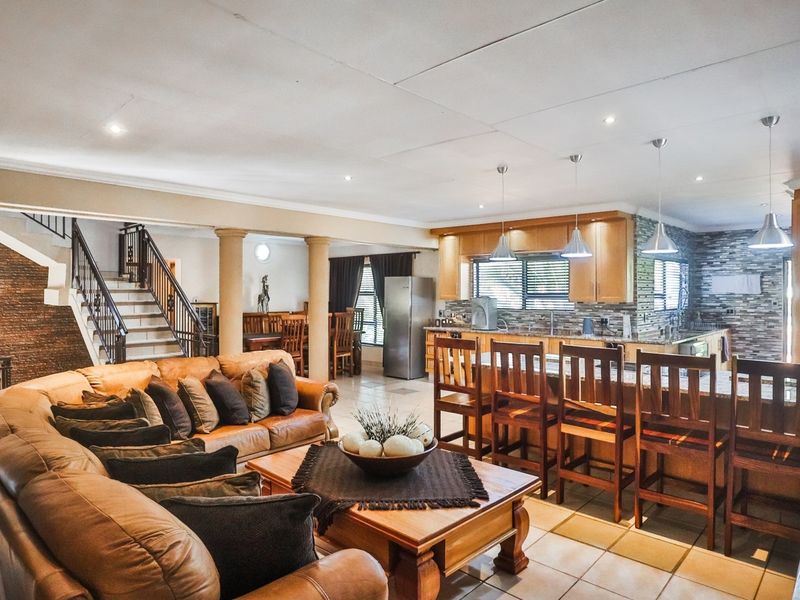 Spacious open-plan living area featuring a modern kitchen with granite countertops, a central island, and an integrated staircase with decorative stone wall accents.