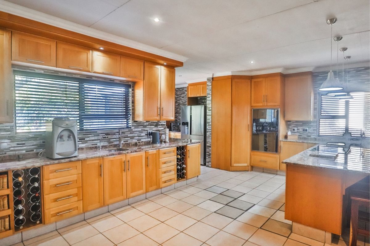 Spacious kitchen featuring warm wooden cabinetry, granite countertops, a central island, and a decorative mosaic backsplash with ample storage and integrated appliances.