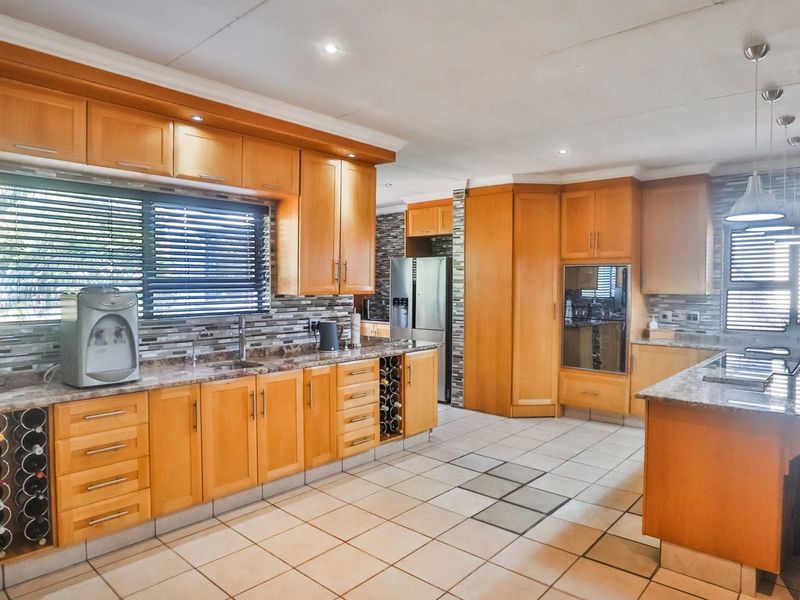 Spacious kitchen featuring warm wooden cabinetry, granite countertops, a central island, and a decorative mosaic backsplash with ample storage and integrated appliances.