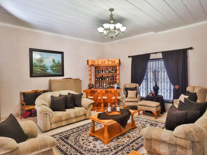 A spacious living room featuring a classic chandelier, tiled flooring, and a tongue and groove ceiling, offering a comfortable and traditional living space.