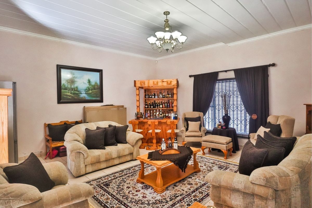 A spacious living room featuring a classic chandelier, tiled flooring, and a tongue and groove ceiling, offering a comfortable and traditional living space.