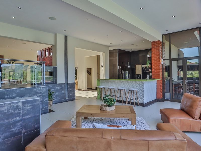 Spacious open-plan living area featuring a modern kitchen with island, tiled floors, recessed lighting, and seamless flow to the outdoor patio area.