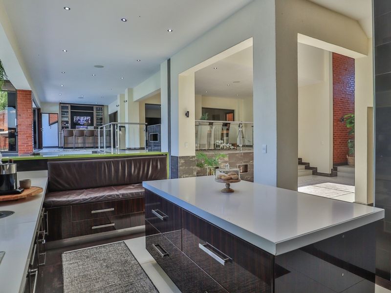 Spacious open-plan kitchen featuring a large central island, modern cabinetry, built-in bench seating, and seamless flow into the adjacent living and dining areas.