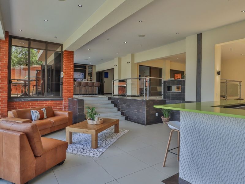 Spacious open-plan living area featuring tiled floors, recessed lighting, a built-in fireplace, and a modern kitchen island, seamlessly connecting to a built-in bar area.