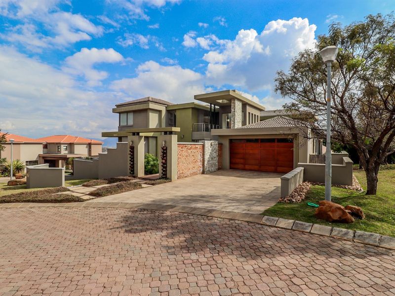 Modern double-story residence featuring a paved driveway, double wooden garage, and attractive stone and brick architectural detailing.
