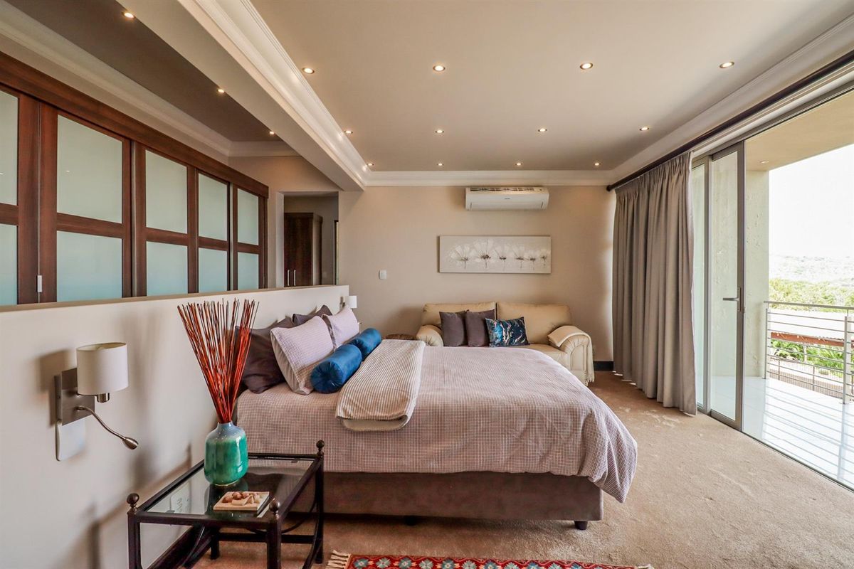 Spacious bedroom featuring recessed ceiling lighting, a wall-mounted air conditioning unit, and sliding glass doors providing access to a private balcony.