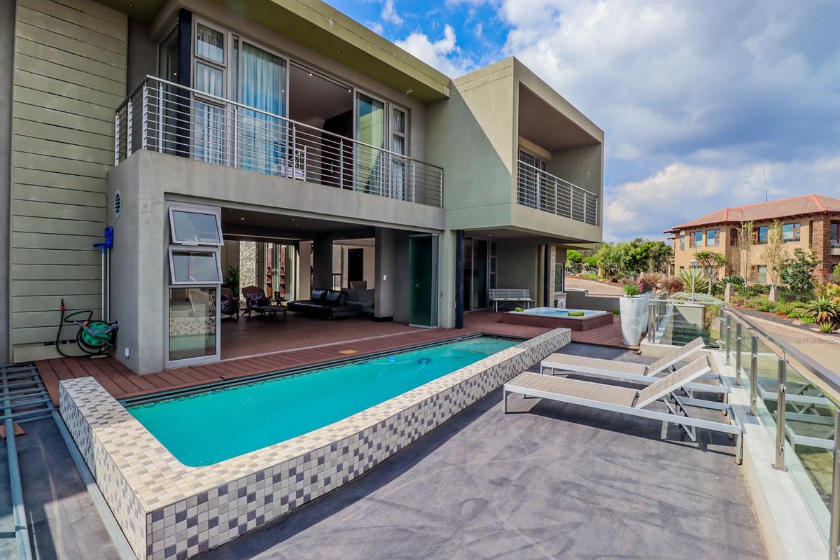 Modern rear exterior featuring a raised swimming pool, timber decking, and upper-level balconies with stainless steel balustrades, offering seamless indoor-outdoor flow.